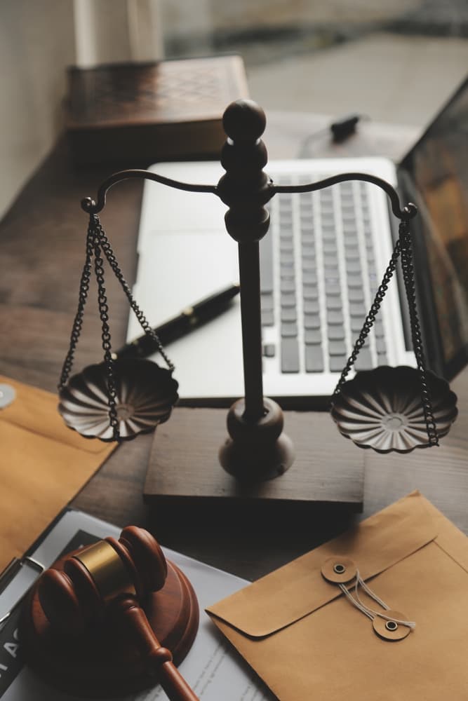 Legal professionals and business executives reviewing contract documents with a brass scale on the desk in an office. Concept image of law, legal services, advice, and justice with a film grain effect.