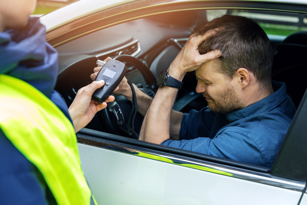 A drunk man sits in his car after the police test him with a breathalyzer.